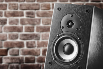 Dark color music speakers. Loud listening music. Music column on the background of a brick wall. © Alexander