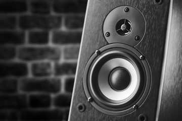 Dark color music speakers. Loud listening music. Music column on the background of a brick wall.