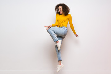 Dominican woman with curly hair jumping over isolated white background