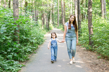 Family and nature concept - Portrait of beautiful woman and child girl walking in summer park