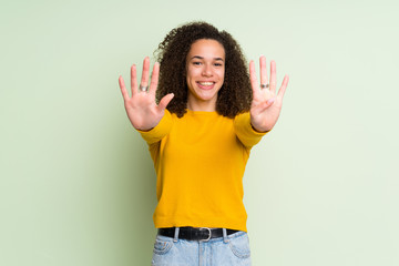 Dominican woman over isolated green background counting nine with fingers