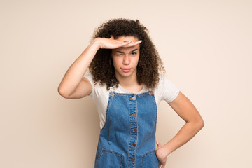 Dominican woman with overalls looking far away with hand to look something