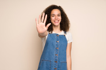 Dominican woman with overalls counting five with fingers