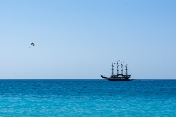 Antient ship and skydiver in the sea. Vacation concept. Summer holidays background