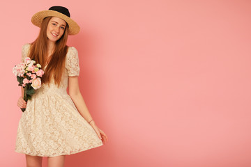 Beautiful, idyllic girl with straw hat and bouquet of flowers.