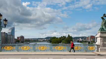 Pont des Arches in Liége, Belgium with woman in red jacket walking on sunny day with clouds