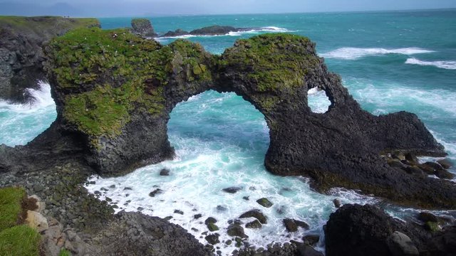 Amazing stone arch Gatklettur basalt rock on Atlantic coast of Arnarstapi in Iceland. The famous natural form arch attracts tourist to visit west of Iceland.