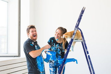 Repair, renovation, pet and love couple concept - young family with cat doing repair and painting...