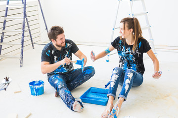 Renovation, redecoration and family concept - Young couple pour paint and having fun