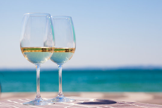 two glasses of chilled white wine on table over Garla Lake backgound