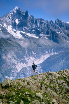 A trail runner, running along a trail in the high alpine mountains of the Mont Blanc range in France