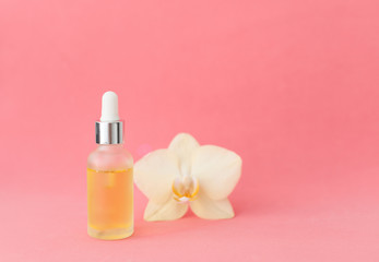 A serum and dropper on a pink background close up, natural cosmetics concept