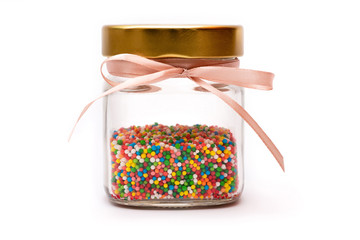 glass jar with a golden tin lid, a pink bow and multicolored candy