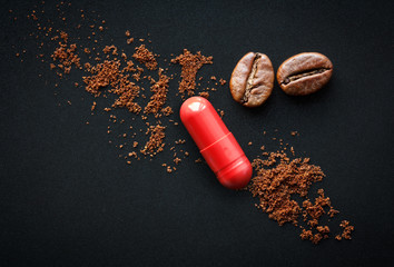 red pill and coffee beans on a black background, the concept of drugs containing caffeine - obrazy, fototapety, plakaty