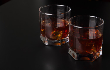 Two glasses of whiskey with ice on a beautiful wooden background