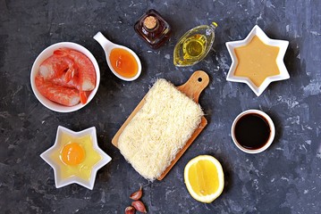 Ingredients for cooking shrimp snack: ready kataifi dough, large shrimp, lemon, peanut butter, soy sauce, egg, vinegar, oil, honey. Asian cuisine. Top view, copy space.