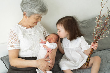 Great-grandmother hugs two great-granddaughters. Grandmother sits with two granddaughters....