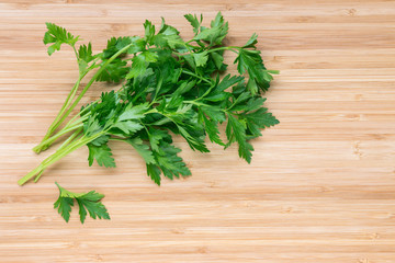 bunch of fresh flat leaf parsley leaves on wooden chopping board with copy space