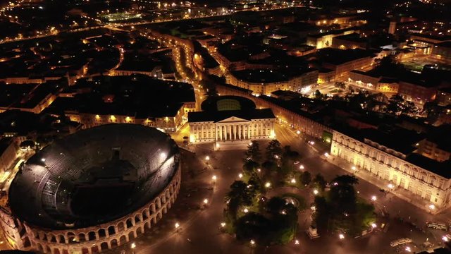 Aerial drone night video from iconic illuminated Arena theatre and City Hall in Bra square of beautiful city of Verona, Lombardy, Italy
