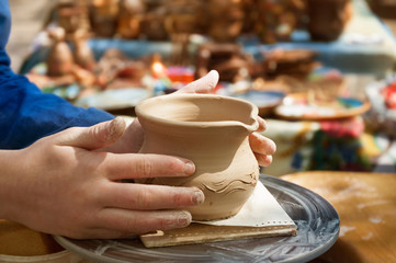 Hands of a potter making ceramic clay product on the pottery whee.