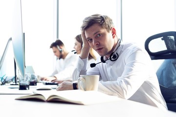 Worried or tired business man with headset working on computer in office.