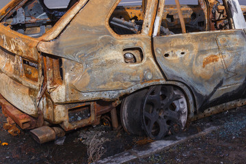 burned down car standing in the middle of the carriageway, in a city that cannot be restored.