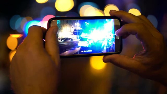 Man recording accident place on smartphone in the night