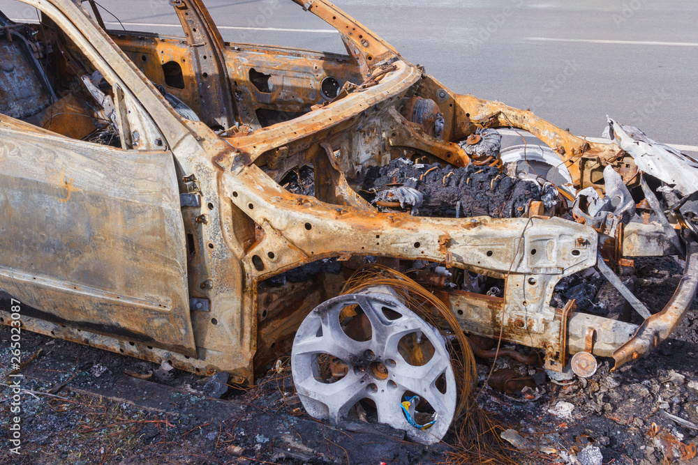 Wall mural burned down car standing in the middle of the carriageway, in a city that cannot be restored.