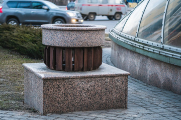 Naklejka premium Decorative design of ventilation. Metal grill on a granite ventilation kiosk. Empty flower bed near the street.