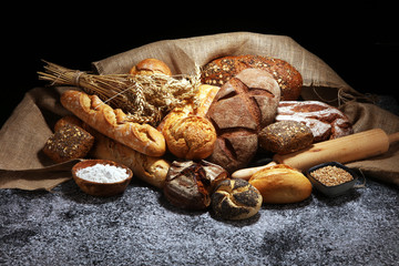 Assortment of baked bread and bread rolls on rustic grey bakery table background