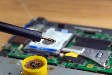 smoke from boiling rosin on a heated soldering iron, disassembled electronic apparatus in the background. selective focus, close