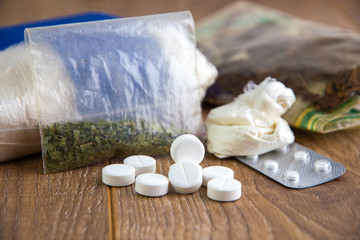Fototapeta na wymiar drug smuggling - a lot of drugs: cocaine, heroin, marijuana, amphetamines are on the table, short focus