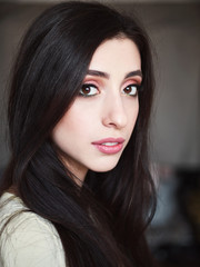 Close up portrait of young beautiful smiling woman with gorgeous long black hair and trendy high end makeup vintage film color tone. Beauty cosmetics and skin care concept.