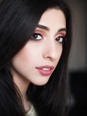 Close up portrait of young beautiful smiling woman with gorgeous long black hair and trendy high end makeup vintage film color tone. Beauty cosmetics and skin care concept.