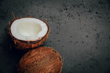 Coconut on a stone background. Whole coconut and opened. Coconuts lie on the counter, the concept of drinking milk and coconut water. Using exotic fruits.