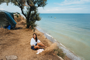 attractive woman in summer skirt and shirt sits on the shore
