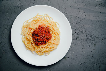 Top view of pasta and spaghetti sauce, tomatoes and peppers on a stone counter top. The concept of eating Italian pasta dishes. Tasty spaghetti on a concrete table. Tomato sauce for pasta.