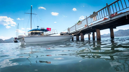 Fototapeta premium Beautiful image of wooden pier with moored yacht and boats at bright sunny day