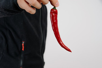 The man holds in his hand chili pepper on a bright white background. The concept of serving...