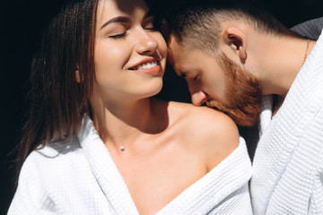 Young man gently kissing beautiful woman on shoulder