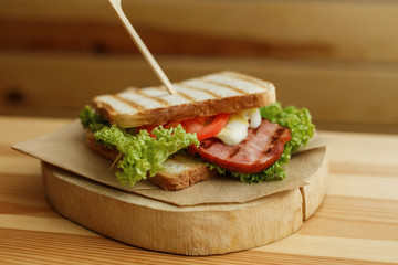 juicy sandwich with grilled bread and bacon wait for you on wooden plate