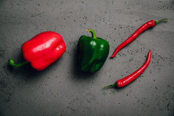 Green and red peppers on a dark background. The concept of preparing meals from vegetables, food for vegetarians, vegans. Healthy food, diet, healthy eating.