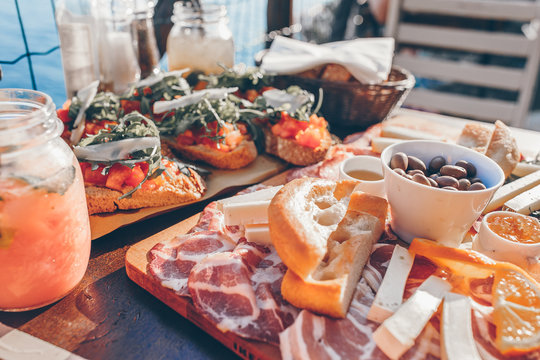 Tasty Italian Snack. Fresh Bruschettes, Cheeses And Meat On The Board In Outdoor Cafe With Amazing View In Manarola