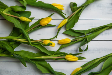 Top view of yellow tulips on a wooden table. The concept of handing flowers to a woman, girl. Beautiful tulips and flowers, mother's day, women's day.