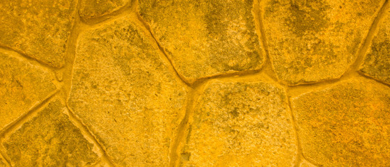 Golden stone surface texture. Natural background in gold color. Texture of stone wall in retro...