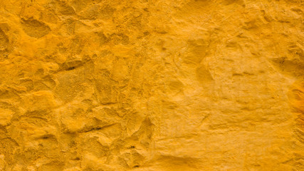 Golden stone surface texture. Natural background in gold color. Texture of stone wall in retro style. Widescreen