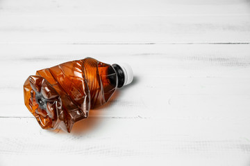 A plastic bottle on a wooden countertop background. Concept of caring for the environment, recycling. Secondary plastic circuit. Environment pollution.