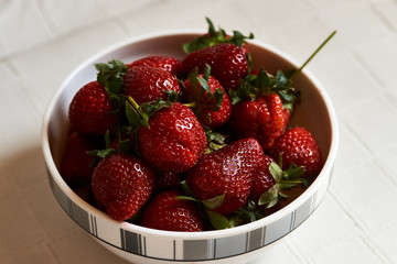 Red fresh strawberry in a bowl on white background with copy space