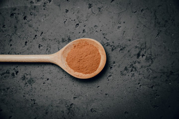 Top view of ground cinnamon on a wooden spoon and a stone counter top. Cookbook, saving recipes. The concept of using seasonings for dishes, various spices on wooden spoons.