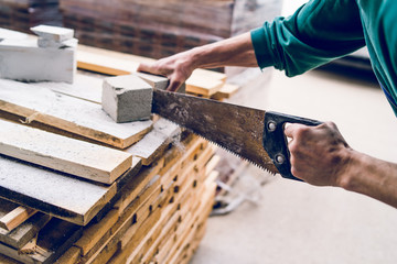 Close up on the construction worker using the hand saw to manually cut the brick insulation material concrete stone